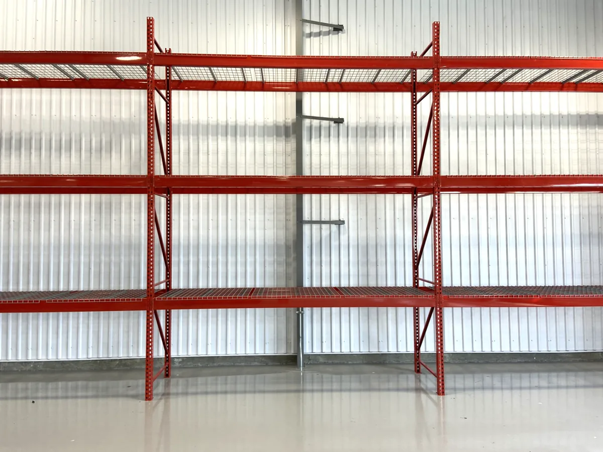 Empty red industrial pallet racking with wire decking